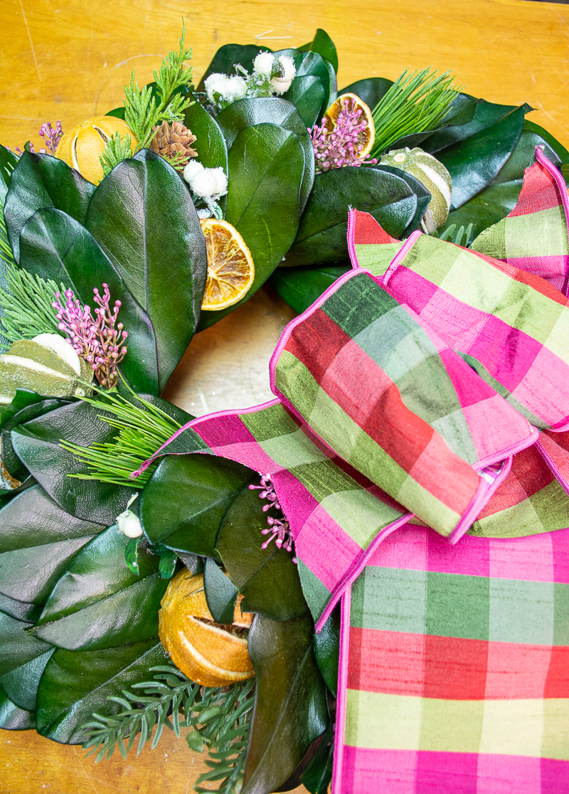 DIY Williamsburg inspired magnolia & citrus Christmas wreath with green and pink plaid bow