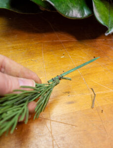 making a pick with evergreen sprigs