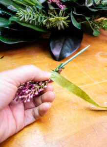 Creating a pick with the pink heather blooms using a wooden floral pick with wire and floral tape