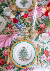 A grandmillennial Christmas table with vintage chintz tablecloth, heirloom silver, Spode Christmas tree china, and rose, peony floral centerpiece