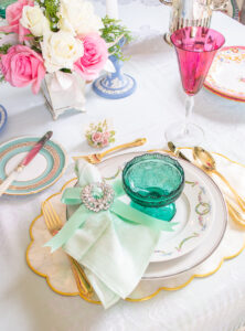 A sparkling vintage brooch tied with mint green bow encircles a linen napkin at this pastel place setting