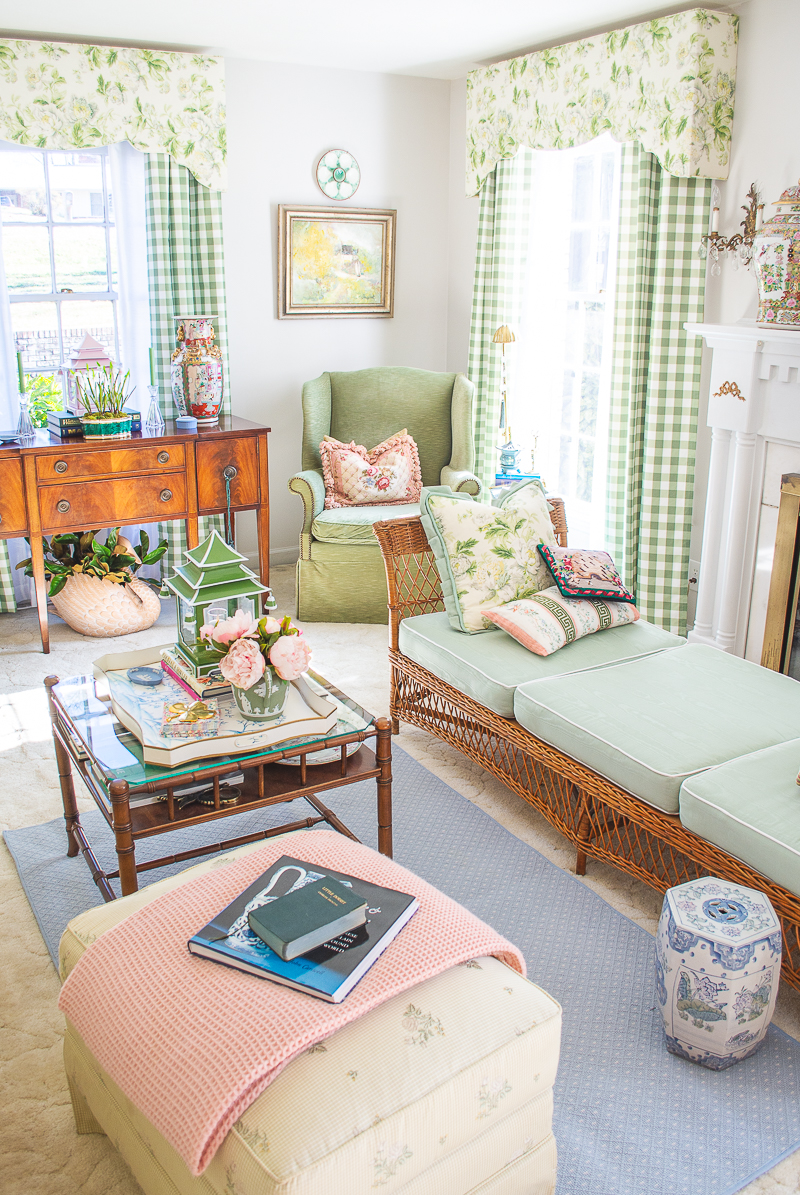 My grandmillennial living room decorated in green, white, blue, and pink with chintz and gingham window treatments, wicker furniture, and colorful accessories.