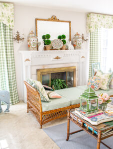 The fireplace in my grandmillennial living room decorated in green, chintz, gingham, and wicker showcases how to decorate with green hues.