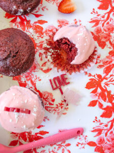 Red velvet cupcakes with strawberry cream cheese frosting on red and pink floral paper