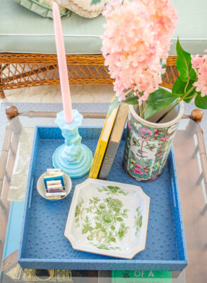 top down view of chinoiserie coffee table with blue tray, dolphin candlestick, and rose canton vase
