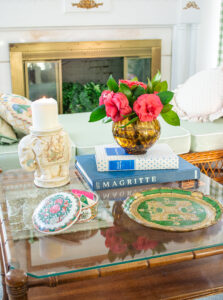coffee table styled with eclectic decor, including a green Florentine tray, rose canton box, elephant candle pillar, and tortoiseshell vase