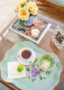 Top view of grandmillennial coffee table styled with tole tray, yellow roses, Wedgwood, Herend, and family photo