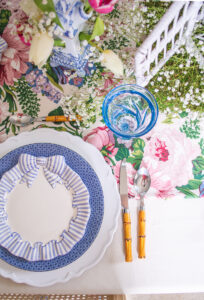 A pacesetting with Haldon Group bow salad plates, Mottahedeh blue lace dinner plates, white chargers, bamboo flatware, and blue glasses