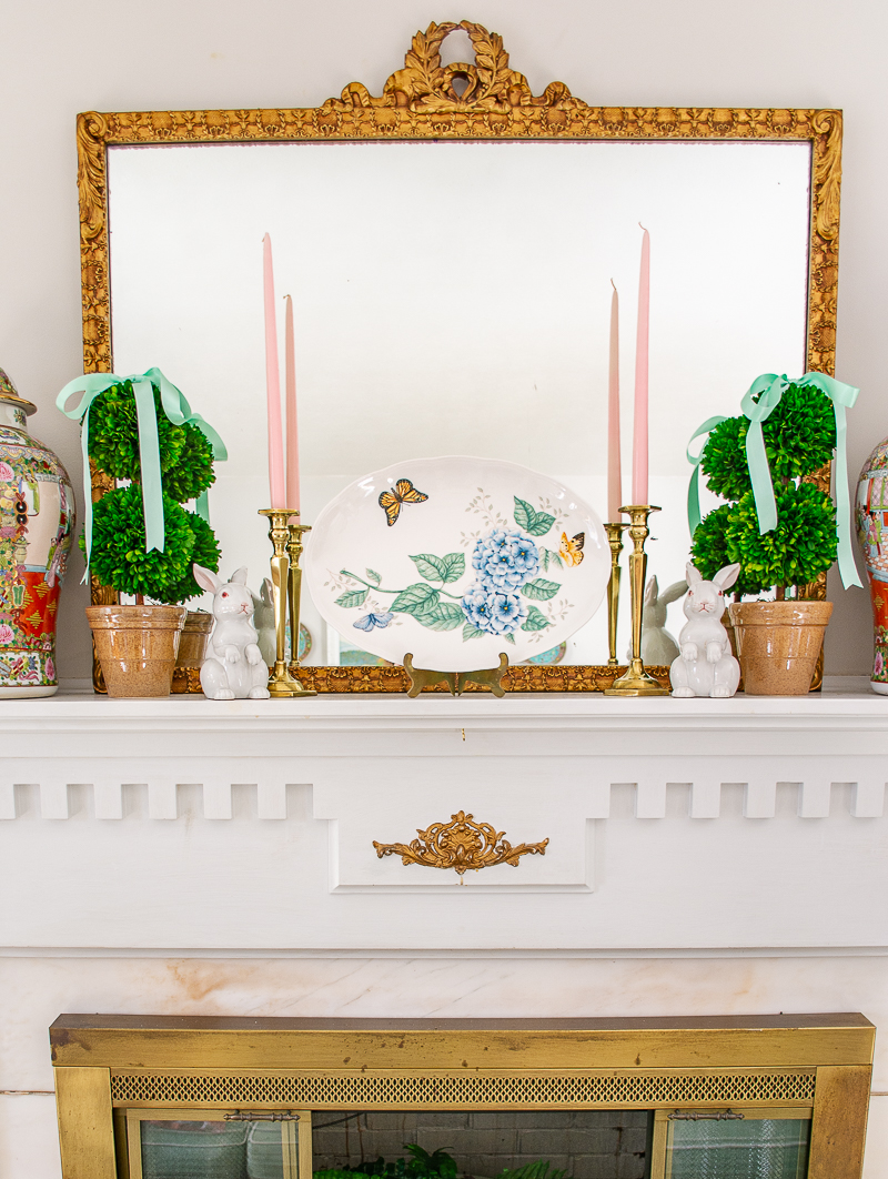 Spring mantel with boxwood topiaries and mint green bows, butterfly meadow platter, and white bunnies