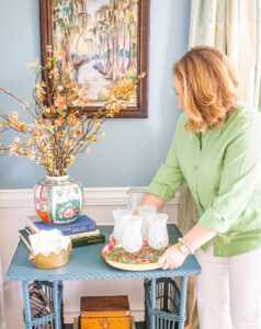Katherine places pretty tin tray with glasses down on table