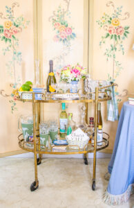 Vintage bar cart decor with brass cart, Art Nouveau screen, and classic barware