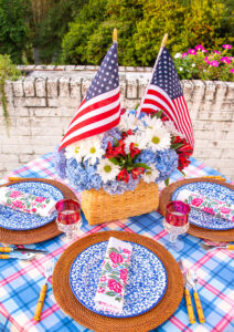 Basket centerpiece with American flags, daisies, blue hydrangea, and red Inca lilies