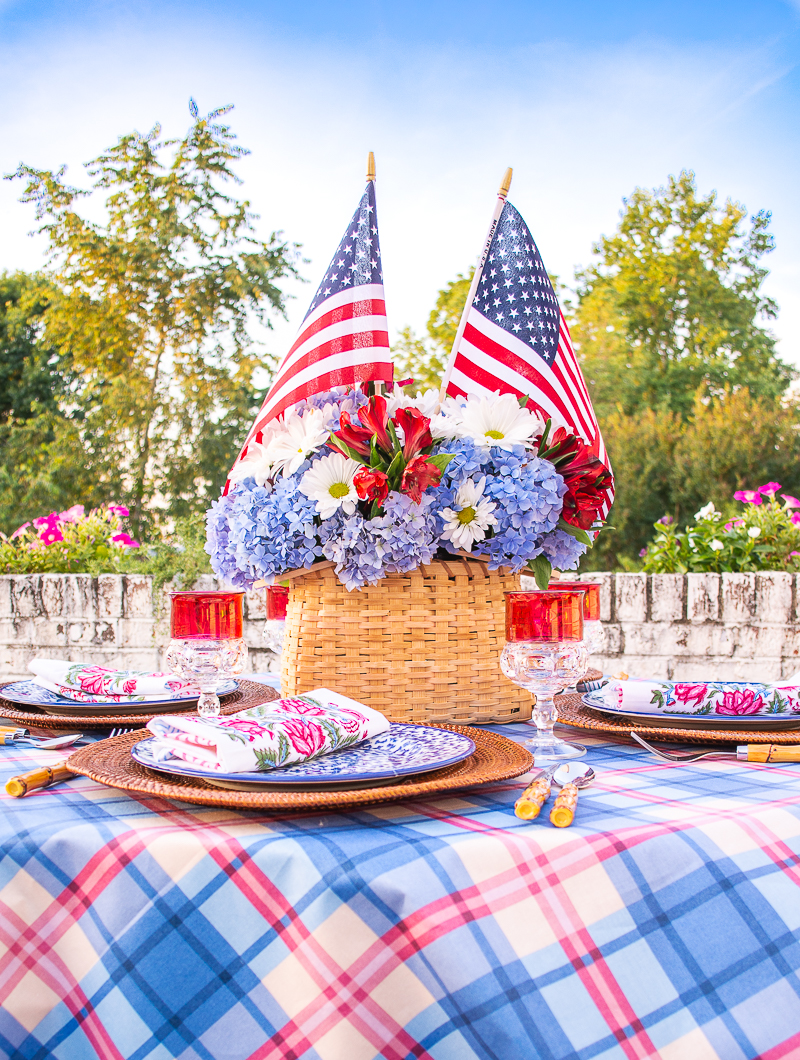 Handmade basket centerpiece filled with blue hydrangea, daisies, and American flags