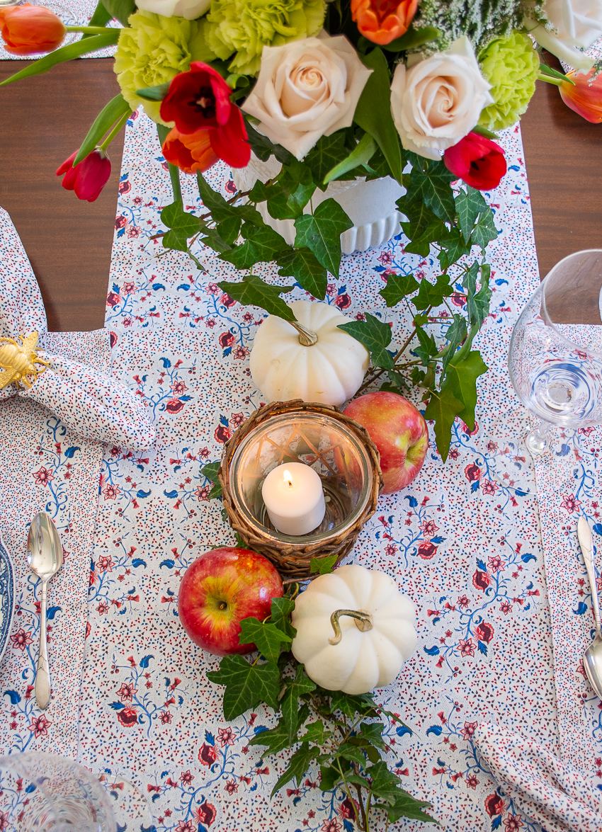 Sarah Flint burgundy floral runner with white pumpkins and red apples nestled amongst ivy vines down center of table