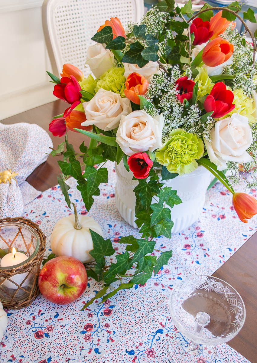 Fall floral centerpiece with white roses, orange and red tulips, lime carnations, and ivy