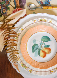 Thanksgiving place setting mixing Mottahedeh fruit plates with Spode's Wicker Dell china, tortoise shell glasses, and bamboo flatware