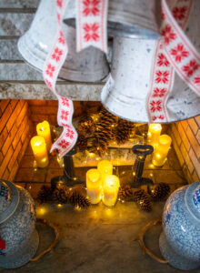 Cozy fireplace with lit candles, pine cones, birch logs, and twinkle lights