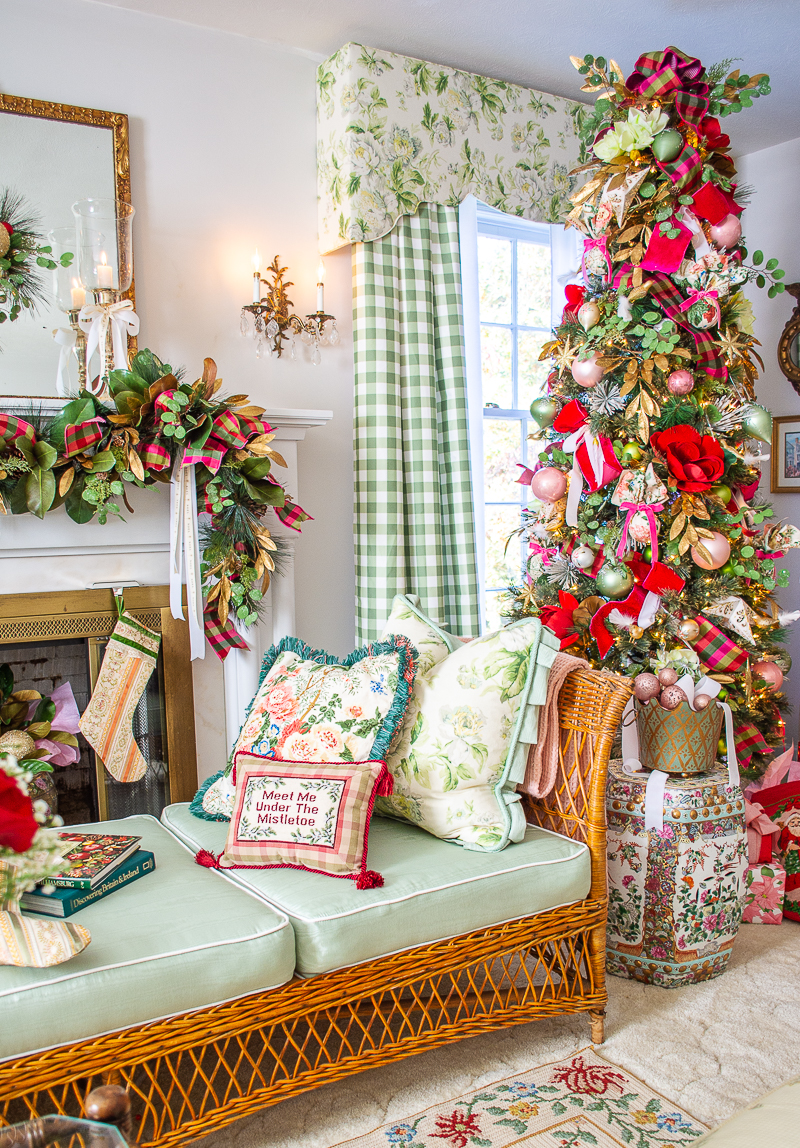 View of my wicker day bed with chintz and needlepoint pillows with pink and green Southern Christmas tree behind