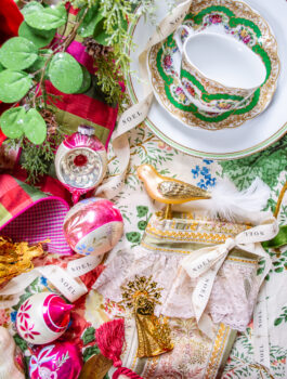 Grandmillennial Southern Christmas inspiration flat lay with plaid ribbon, magnolia, vintage baubles, and Althea Hollyhock Lee Jofa fabric