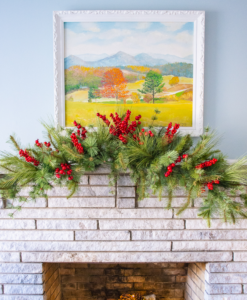Red berries added to faux pine swag for a cozy Christmas mantel