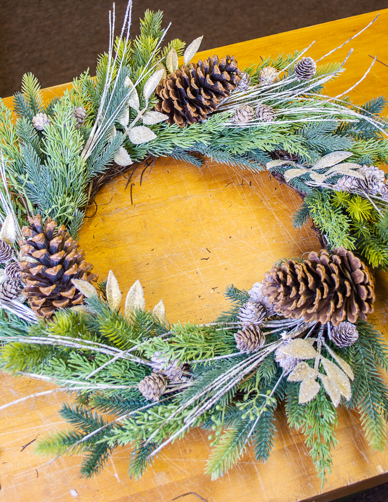 mixed evergreen wreath with additional gold leaves and winter twigs added