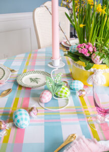 plaid Easter eggs, lily of the valley tole candle holders, and Lindt candies decorate the middle of this plaid Easter tablescape