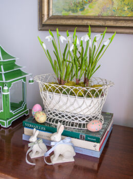 Vintage decor for a taste of spring: white wire basket filled with faux snowdrops, porcelain bunnies, and painted easter eggs adorn this sideboard