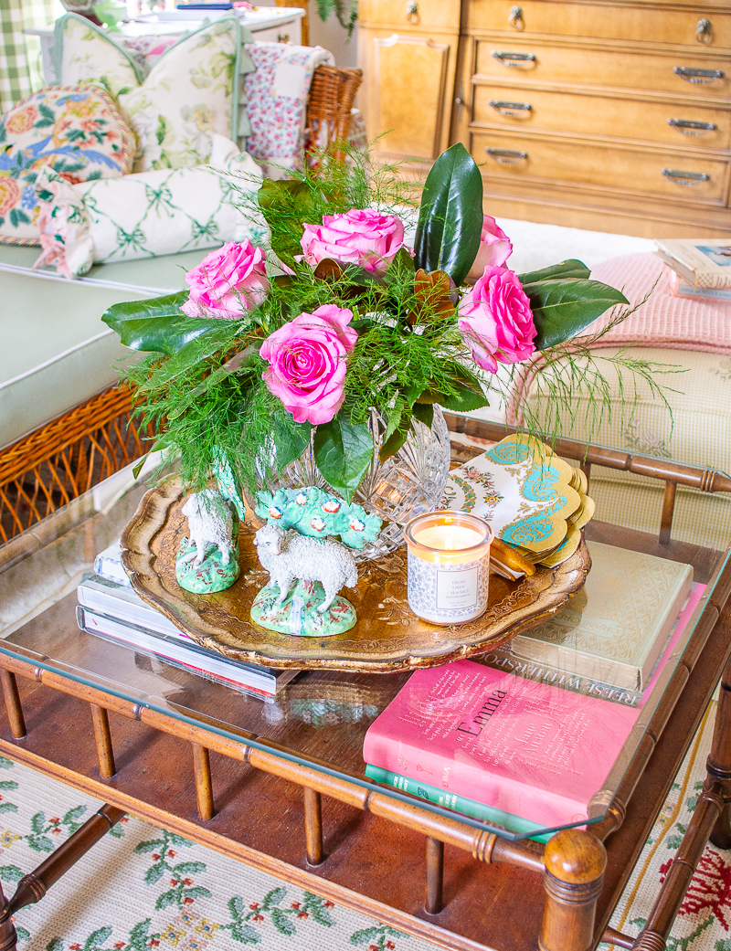 Coffee table in grandmillennial living room showing how to mix high and low end decor with inexpensive books and candles paired with a Waterford crystal vase and Staffordshire sheep