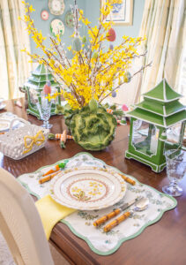 Green and yellow spring tablescape with yellow bell centerpiece, pagoda lanterns, and Spode Wicker Dell dishes