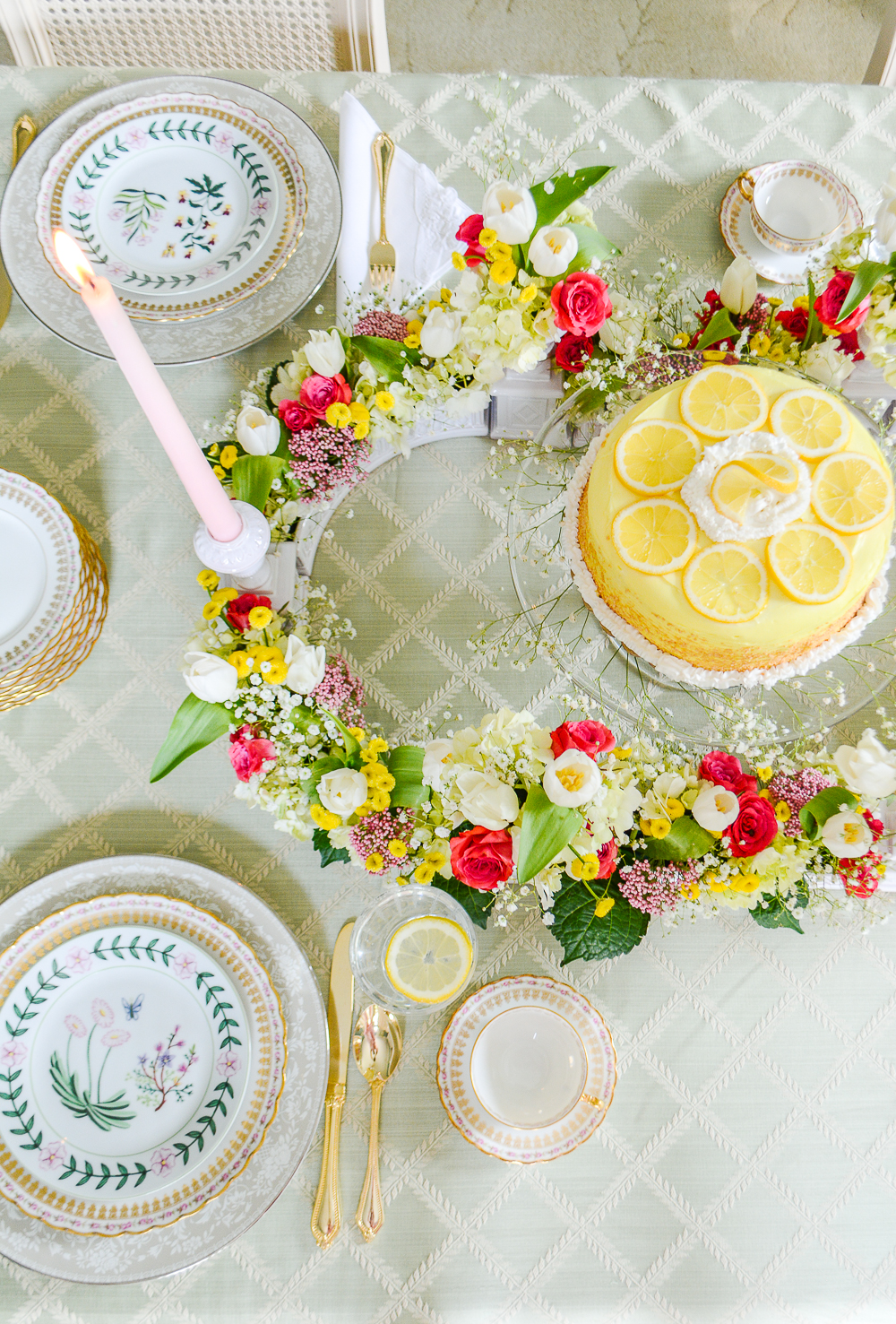 top view of Regency inspired shower tablescape with lemon cake, pink, green, and yellow florals, laurel leaf tablecloth in pale green, and botanical china