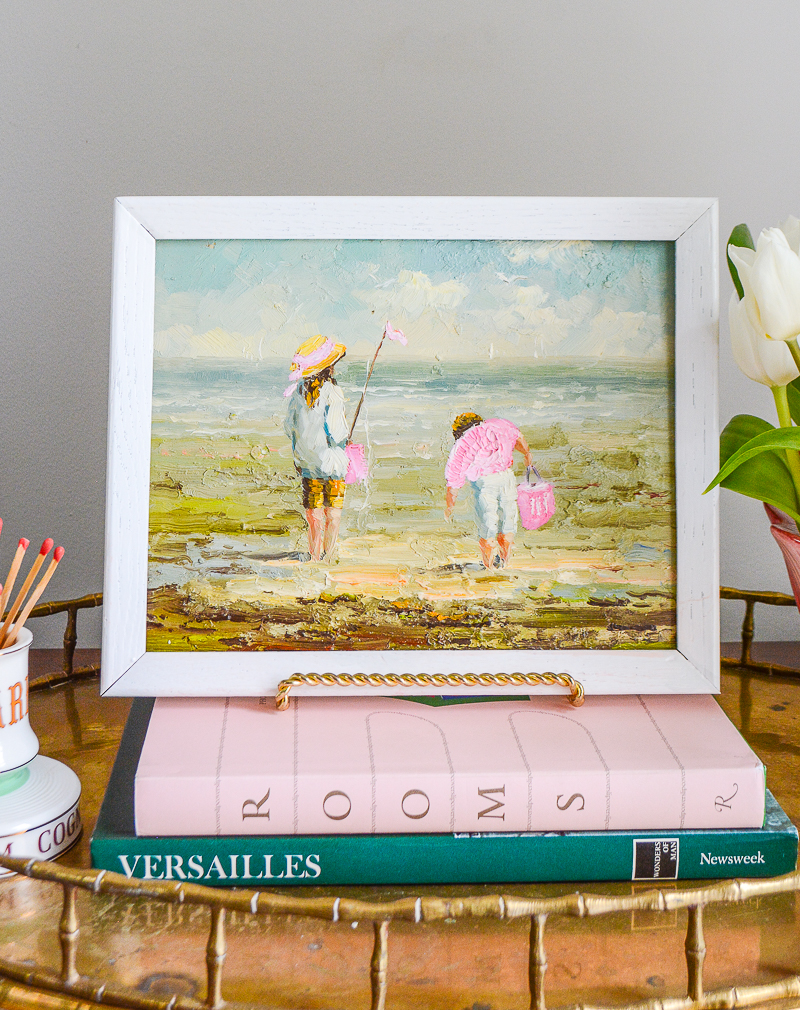 Small painting on table top easel of children playing in the sand at the beach.