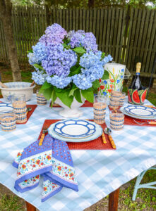 summer tablescape with hydrangea centerpiece, red, white, and blue theme, gingham tablecloth, bamboo plates, and Italian floral napkins