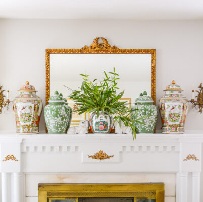 Summer mantel decorated with green and white floral temple jars, Rose Medallion temple jars, live bamboo greenery, and Staffordshire spaniels.