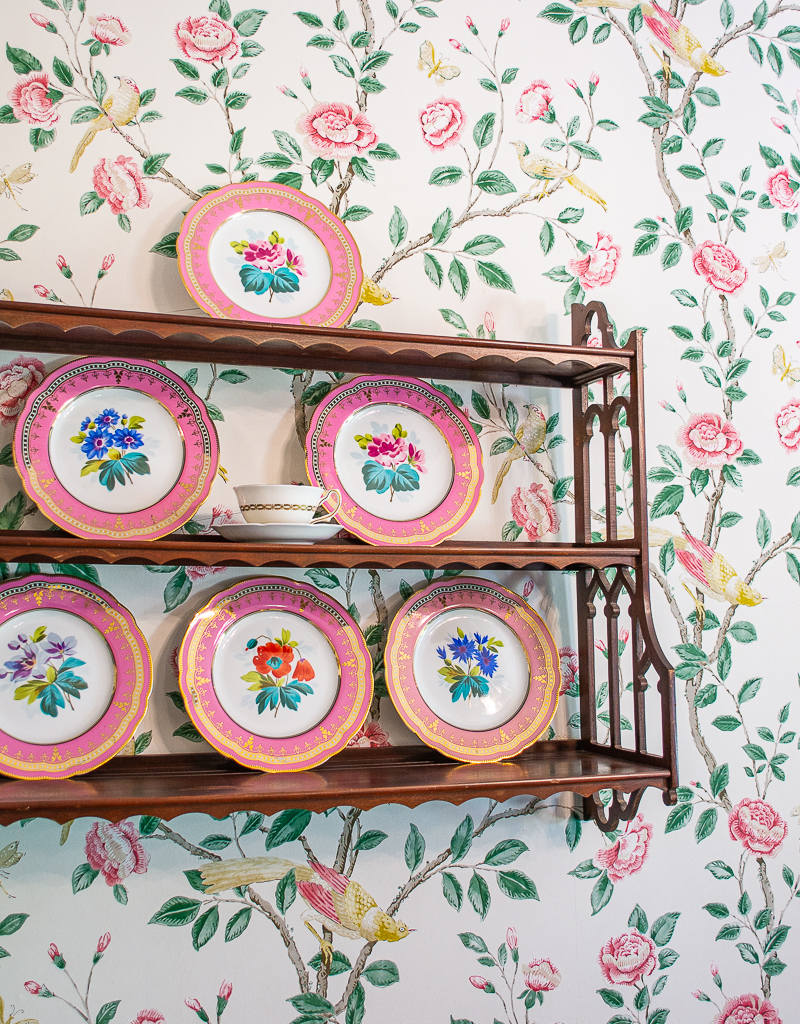 Floral Chinoiserie wallpaper with birds behind a wall shelf with pink floral plates