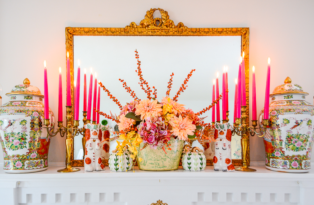 Hot pink tapered candles in vintage brass candelabras with an autumnal floral arrangement and ceramic pumpkins decorate this fall mantel