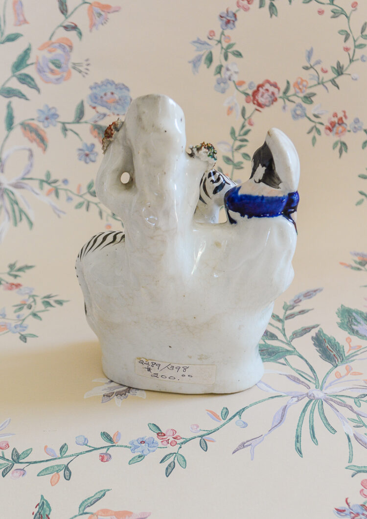 Staffordshire flatback girl with zebra, spill vase in orange and white
