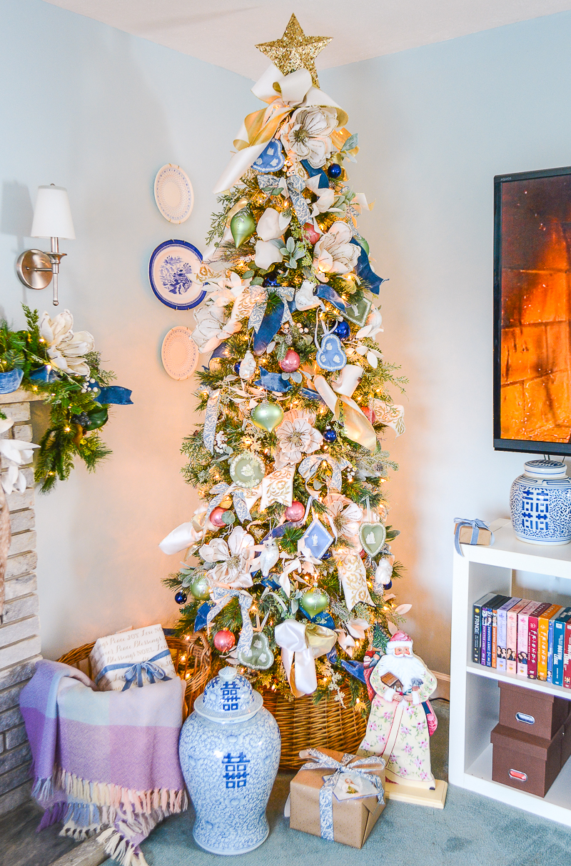 This frosted pastel Christmas tree is decked in blue and white ribbons, pastel baubles, Wedgwood ornaments, magnolia, and gold star topper.