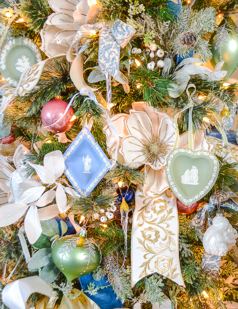 White glittered felt magnolias, embroidered ribbons, Wedgwood ornaments, and pink baubles create a cheery Christmas tree in pastel hues.
