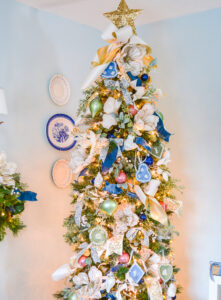 This frosted pastel Christmas tree is decked in blue and white ribbons, pastel baubles, Wedgwood ornaments, magnolia, and gold star topper.