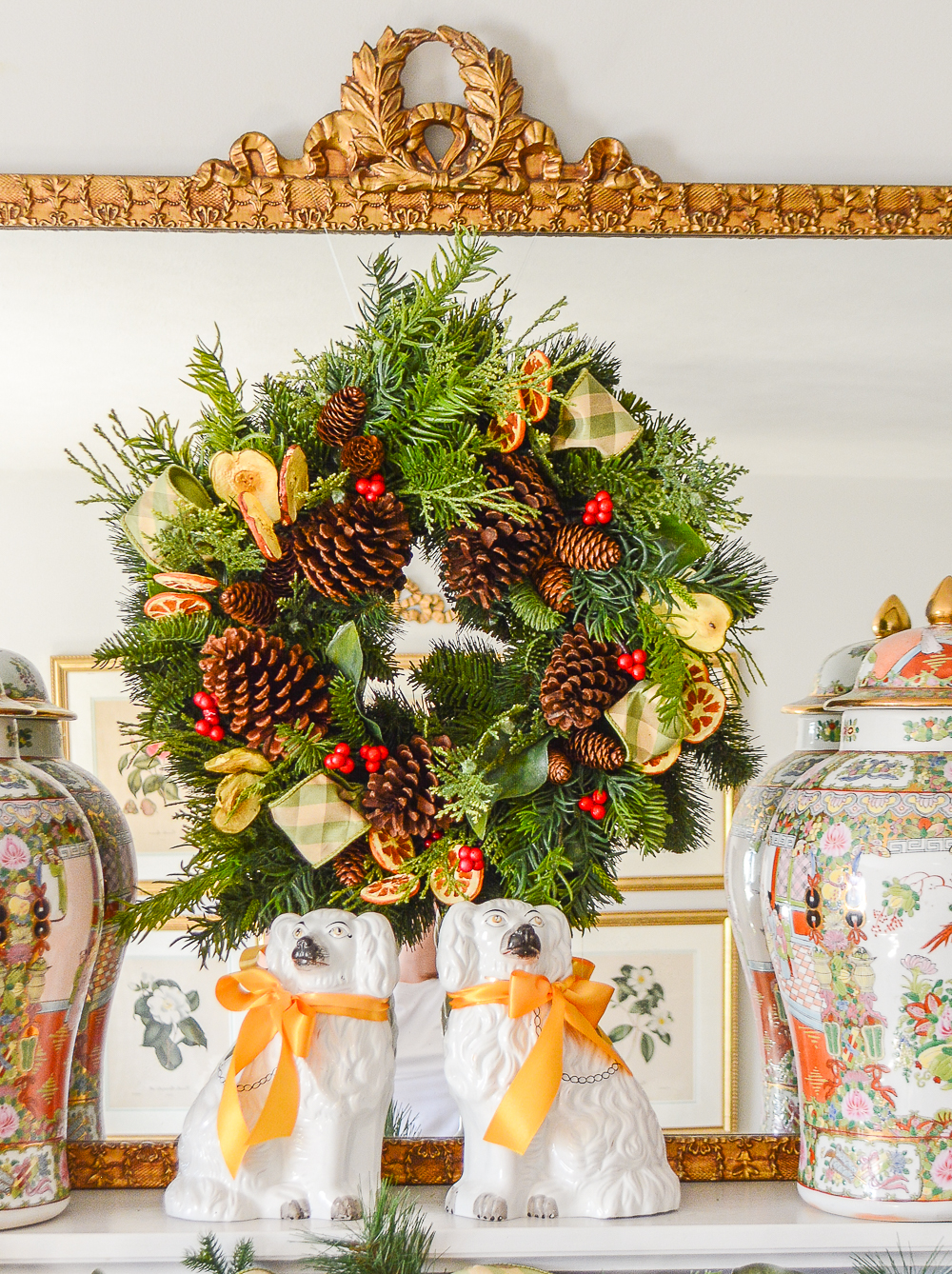 One faux evergreen wreath decorated two ways with pinecones, fruit slices, and plaid ribbon.