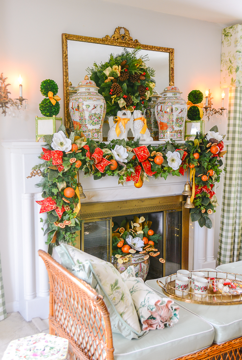 A mixed pine and magnolia garland with orange pomanders, red velvet ribbon, ivy, and white magnolia blooms swags across the traditional mantel.