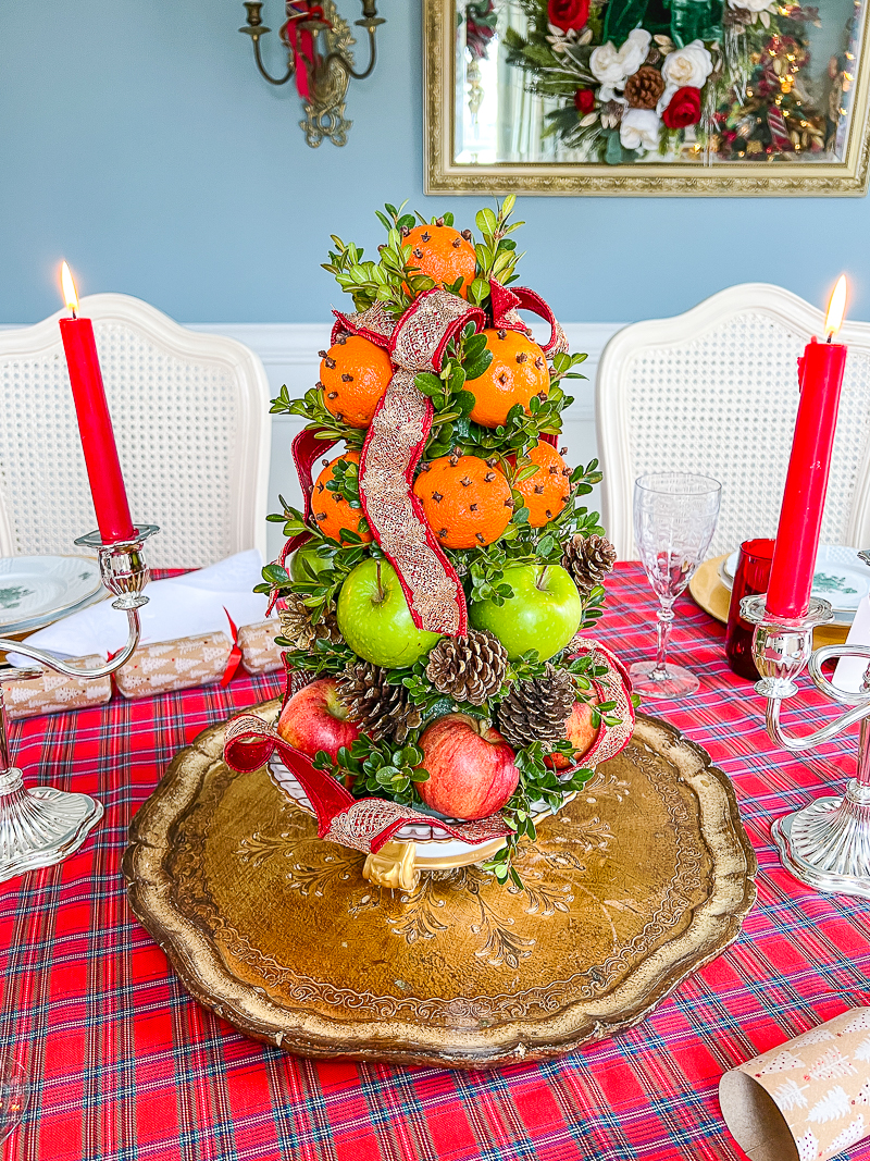 How to make a Williamsburg inspired fruit topiary with apples, mandarin oranges, pinecones, and ribbon.