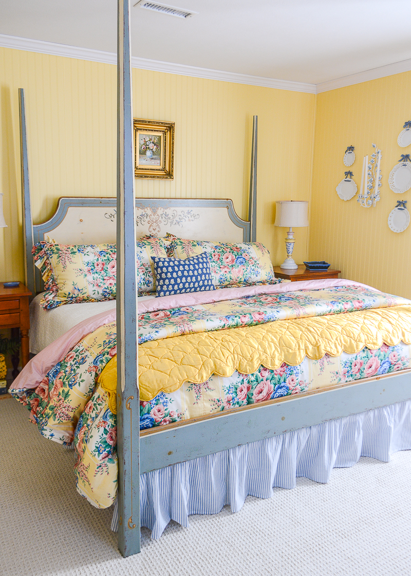 A cozy happy guest bedroom decorated in yellow and blue with floral chintz bedding, hand painted furniture, original art, and anitques!