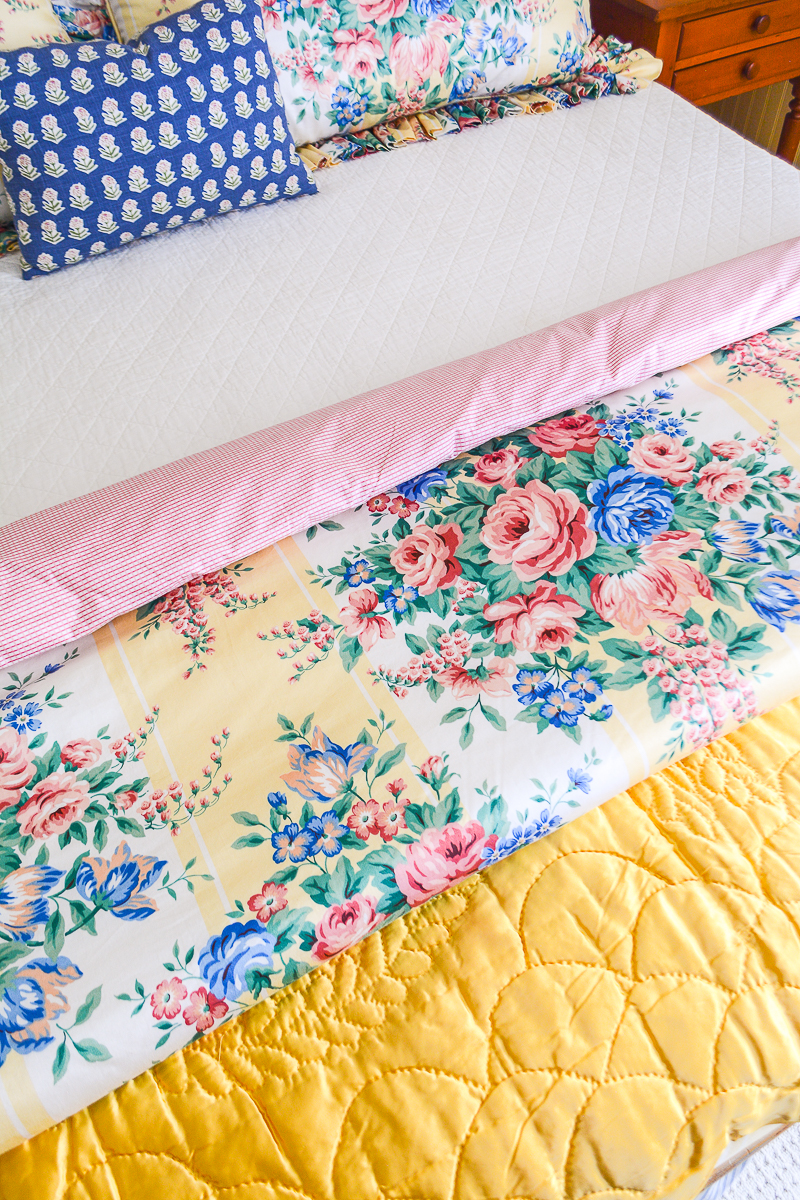 Detail view of layered comforter and quilt on this guest bed