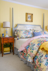 Vintage chintz bedding in yellow, pink, and blue gives those traditional but playful Grandmillennial vibes