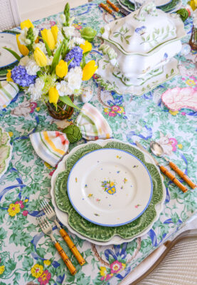 An Easter table with bunnies and bows set with a vintage cloth, cabbage ware, and floral plates