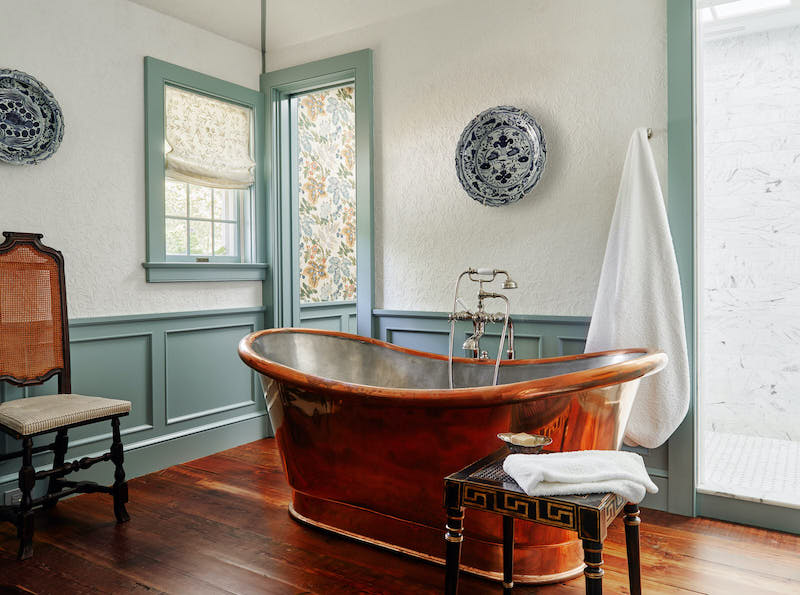 Bathroom with copper tub and blue and white chargers on walls designed by Lilse McKenna