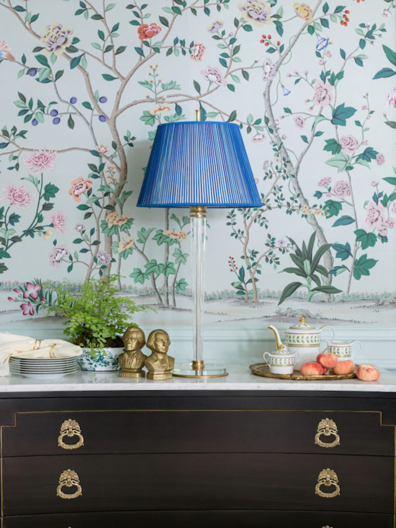 Pale blue chinoiserie wallpaper with indigo lamp and black buffet