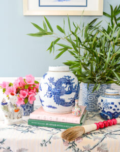 Collection of blue and white Chinese porcelains on skirted table with bamboo branches, calligraphy brush, and pink flowers - the right way to do blue and white!