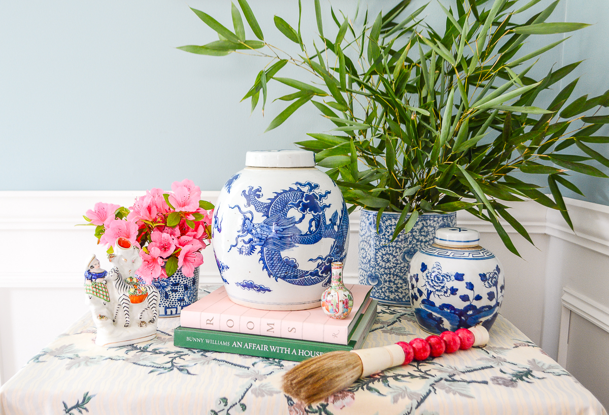 Collection of blue and white Chinese porcelains on a skirted floral table with bamboo stems and pink flowers - a blue and white done right vignette